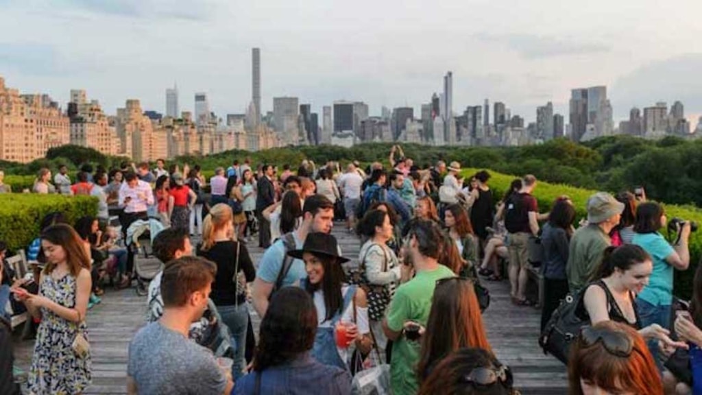 Extérieur d'un Rooftop rempli de personnes qui parlent, avec vu sur la Skyline de New York.